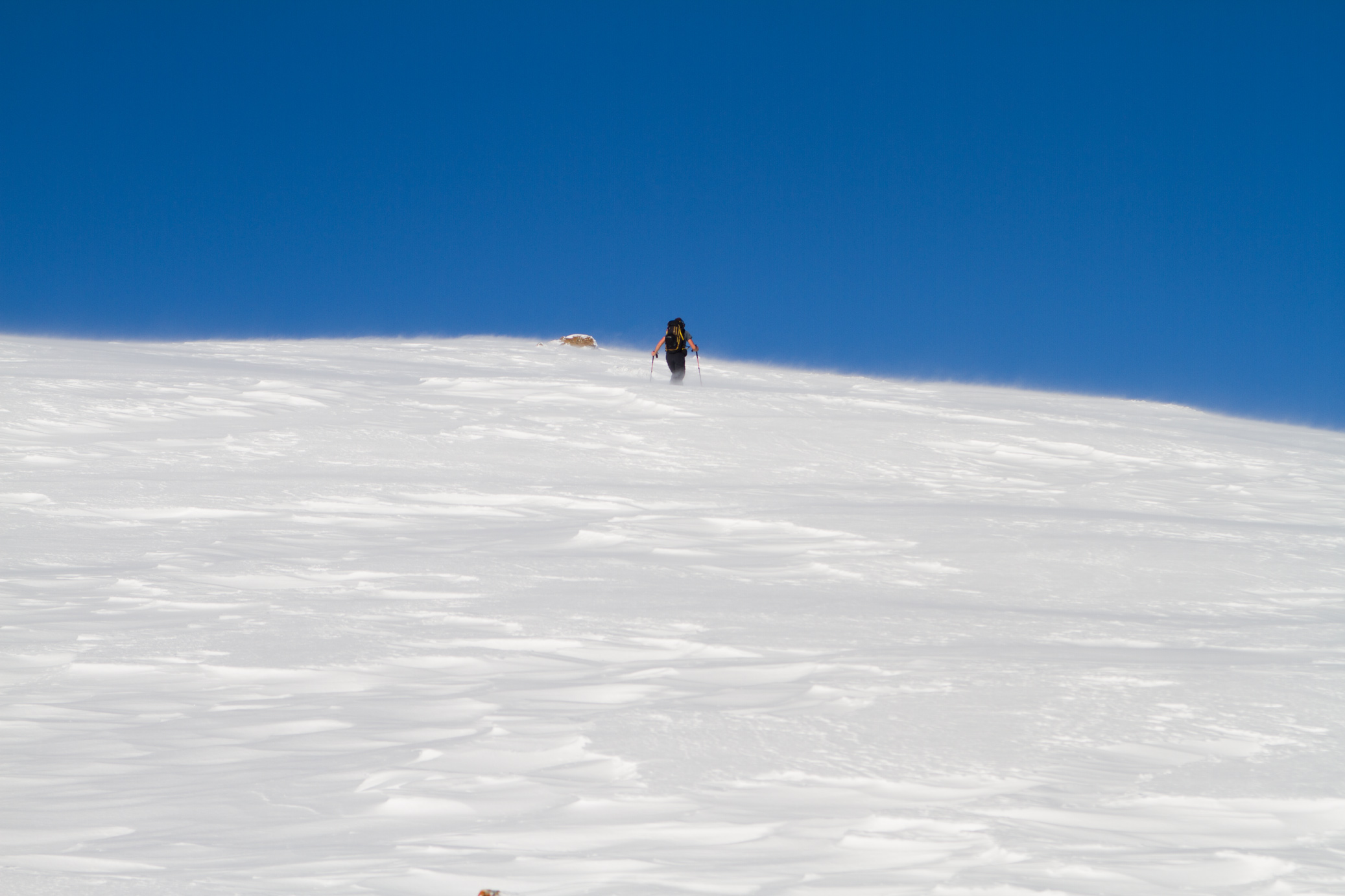 Skitour im Wipptal. Ein Skitourengeher der durch Tiefschnee geht bei starkem Wind.