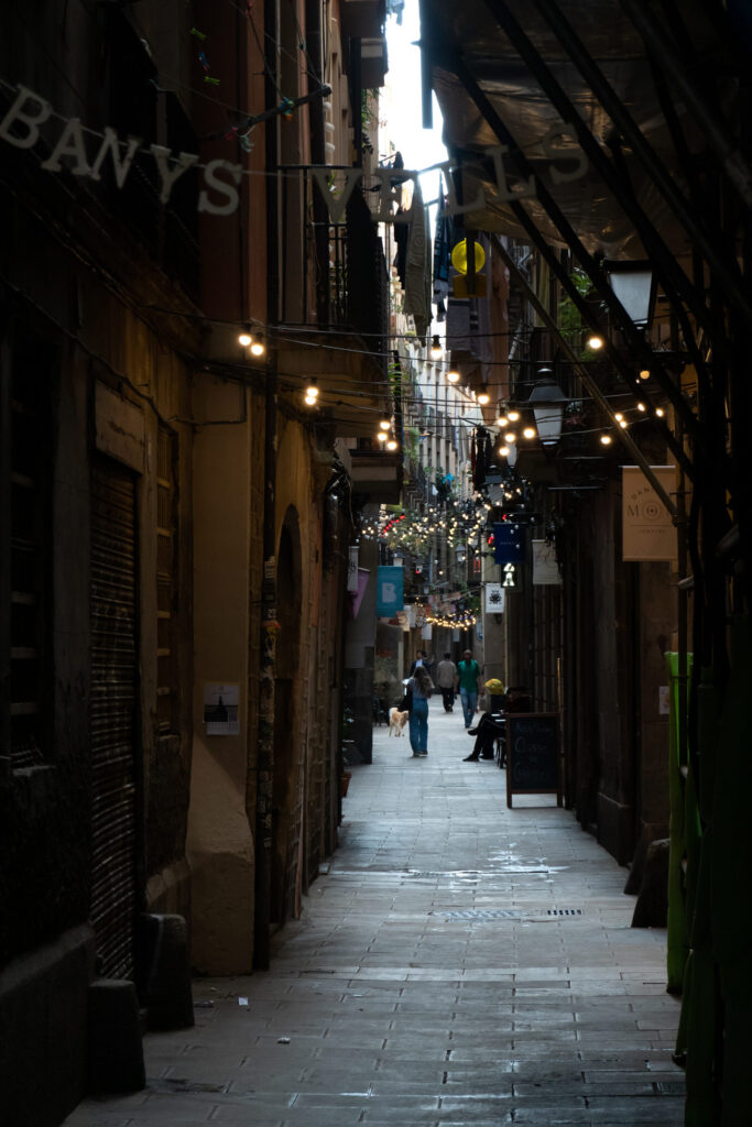 Das Barri Gòtic oder Barrio Gotico in Barcelona mit einer dunklen schmalen Gasse in der Lichter leuchten.