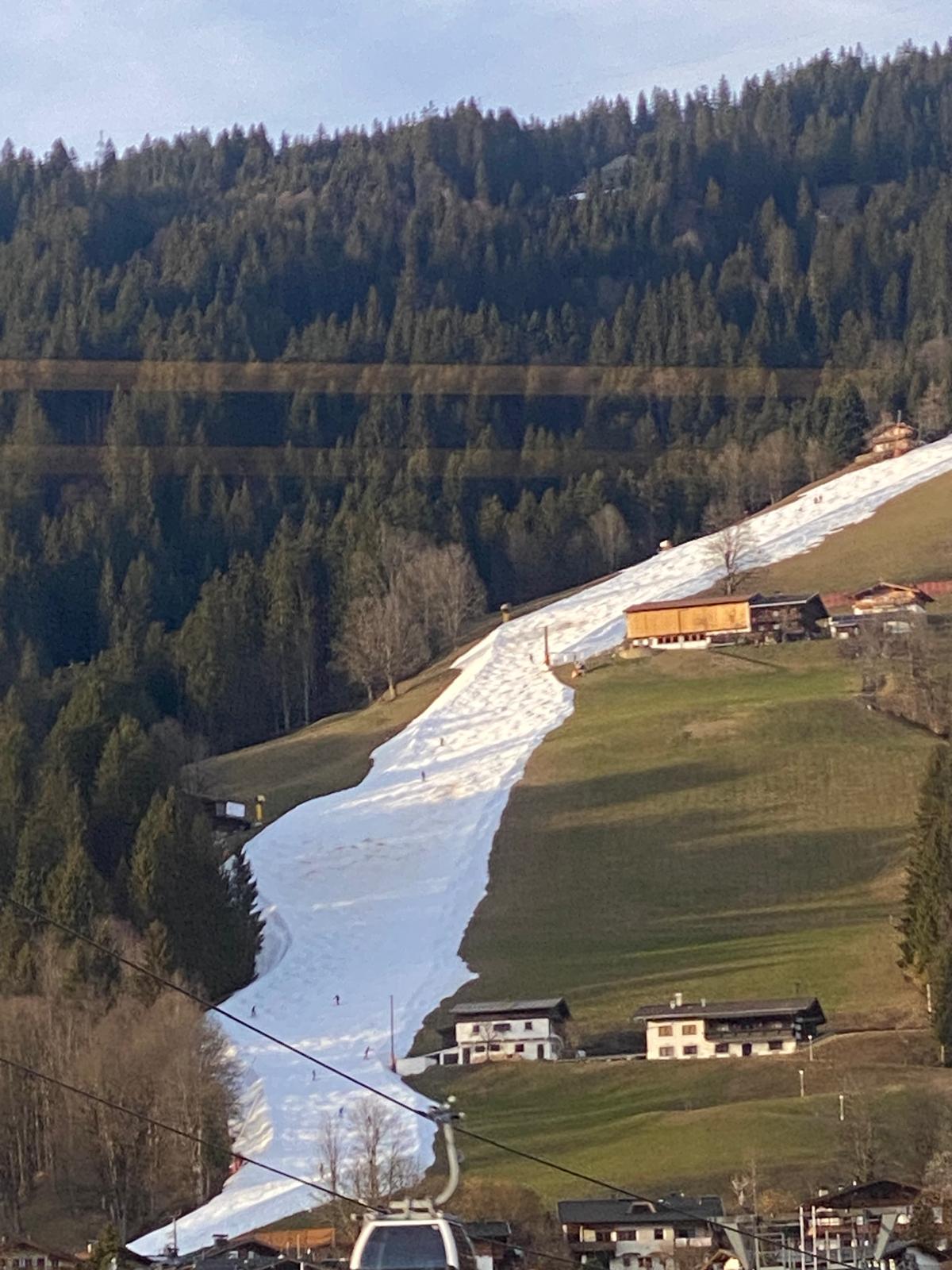 Eine Skipiste in Tirol als weiser Streifen auf grünen Wiesen. Nachhaltigkeit im Tourismus ist eine Gradwanderung.