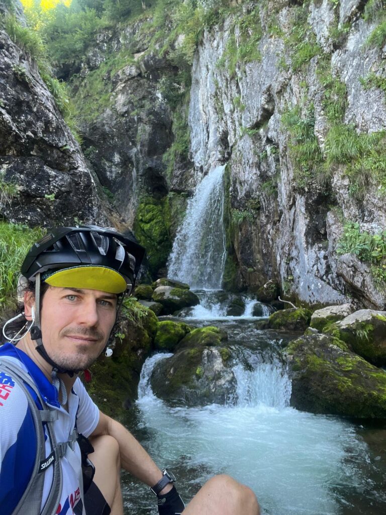 Der Dachserfall, ein Wasserfall bei Abtenau auf einer Gravelbiketour. Ein Radfahrer sitzt vor dem Wasserfall.
