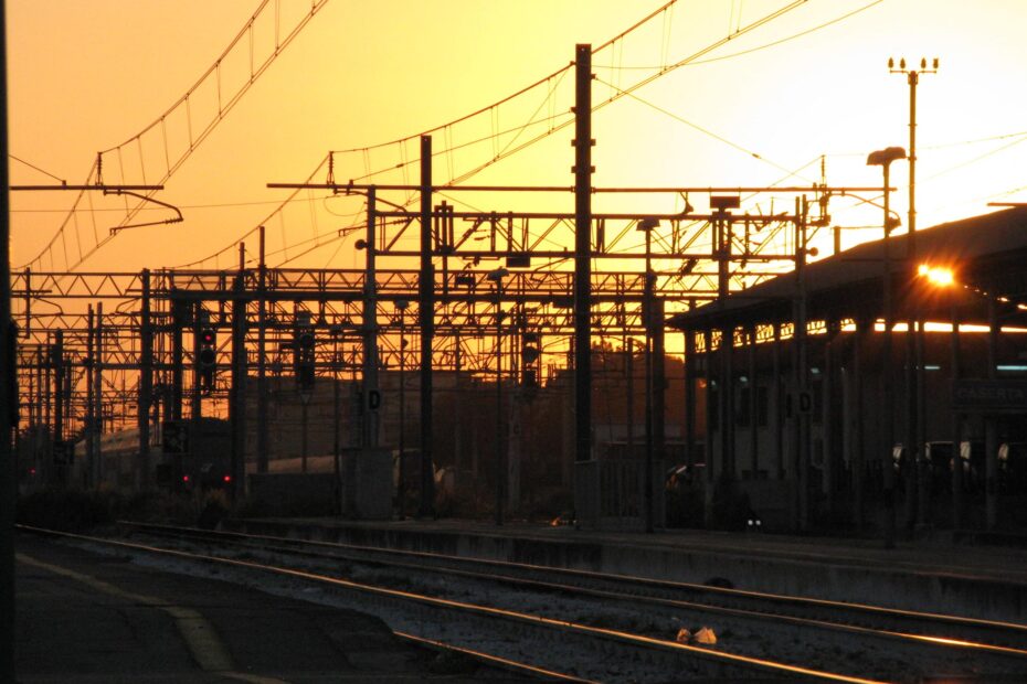 Ein Bahnhof in Italien bei tiefrotem Sonnenuntergang.
