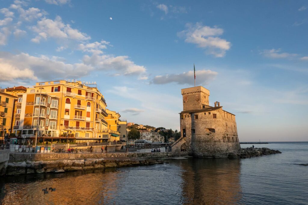 Sonnenuntergang über der Küste vor Rapallo, Ligurien mit Blick auf die Burg im Meer.